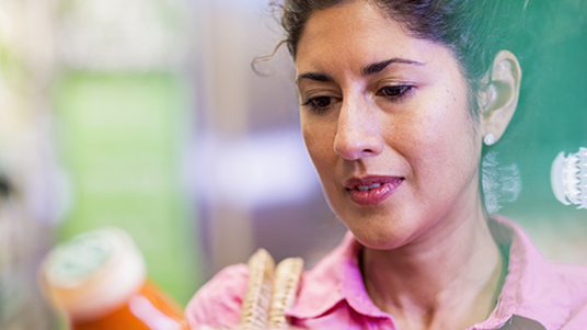 Primer plano de una mujer examinando una botella de alimento