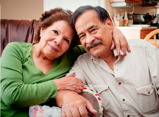 Una pareja de mediana edad, hombre y mujer, abrazados sonriendo gentilmente a la camara